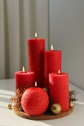 Burning candles with Christmas decor on white table
