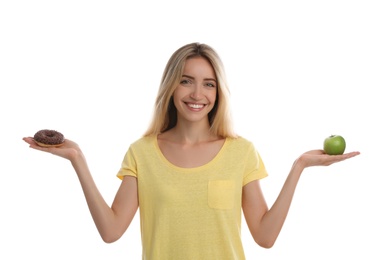 Woman choosing between doughnut and healthy apple on white background