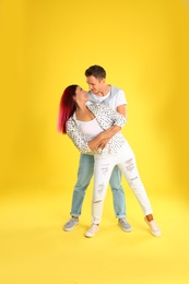 Beautiful lovely couple dancing on yellow background