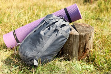Photo of Sleeping bag and camping mat near tree stump outdoors