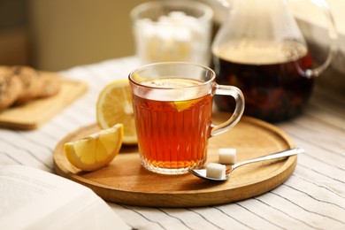 Glass mug of aromatic tea with lemon and sugar on table