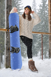 Young woman with snowboard wearing winter sport clothes and goggles outdoors
