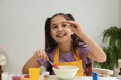 Photo of Cute little girl making slime toy at table indoors