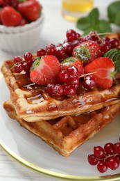Photo of Plate of delicious Belgian waffles with berries and honey on table, closeup