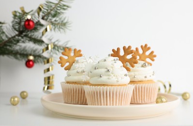 Tasty Christmas cupcakes with cream and snowflake cookies on white table