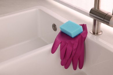 Sponge and rubber gloves on kitchen sink indoors