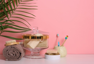 Composition of glass jar with luffa sponges on table near pink wall. Space for text