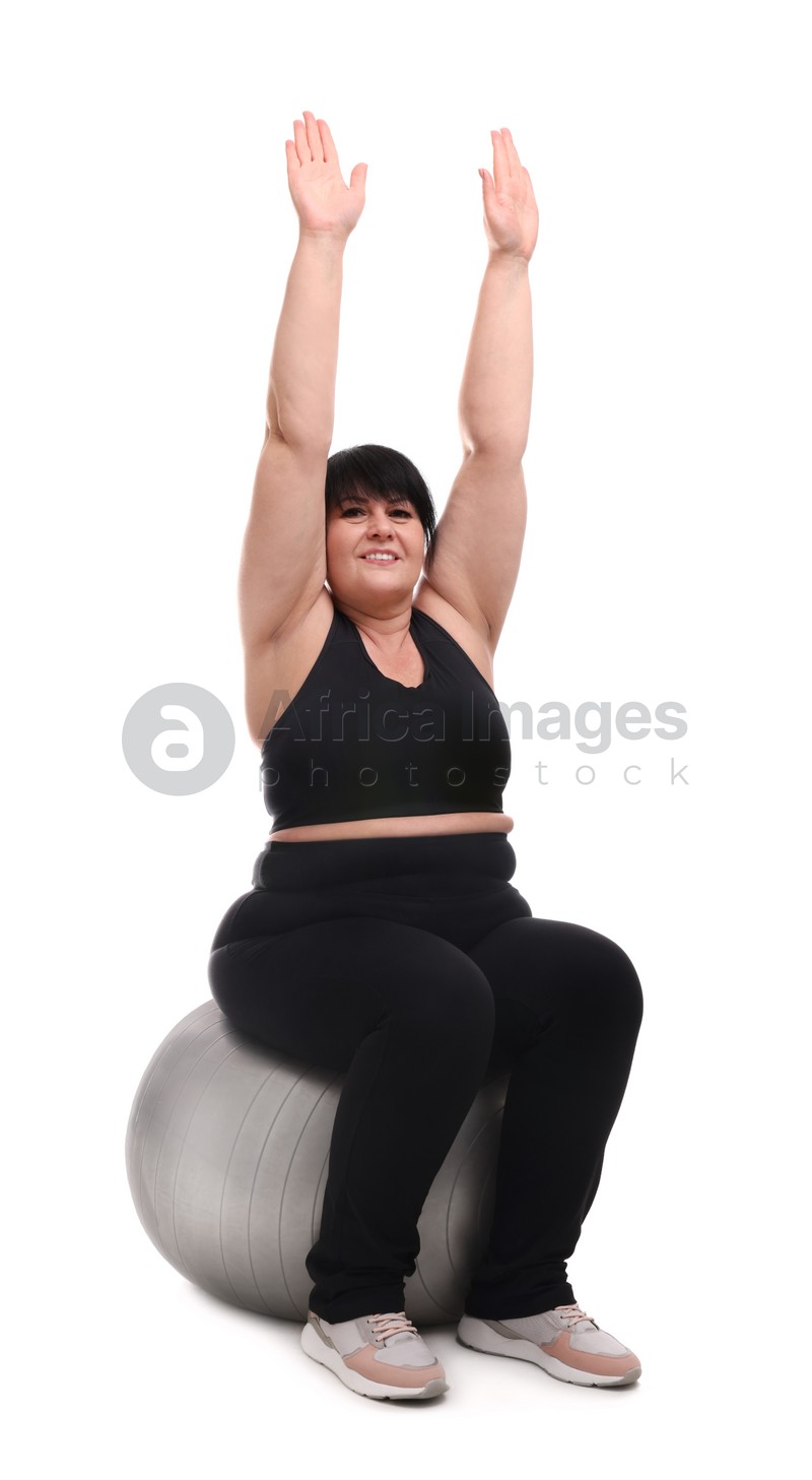 Happy overweight mature woman sitting on fitness ball against white background