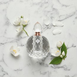 Bottle of luxury perfume and fresh jasmine flowers on white marble table, flat lay