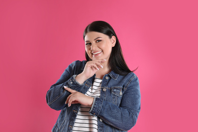 Photo of Beautiful overweight woman posing on pink background. Plus size model
