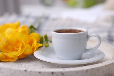 Cup of morning coffee and flowers on tray indoors, closeup