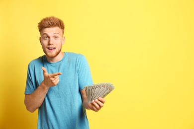 Portrait of surprised lottery winner with money on yellow background, space for text