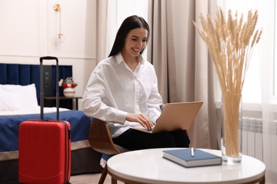 Beautiful young business woman working with laptop in hotel room
