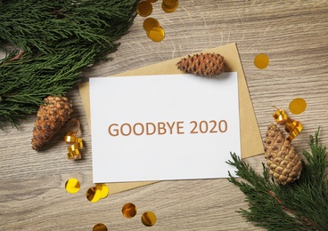 Photo of Card with text Goodbye 2020 and festive decor on wooden background, flat lay