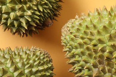 Fresh ripe durians on orange background, closeup