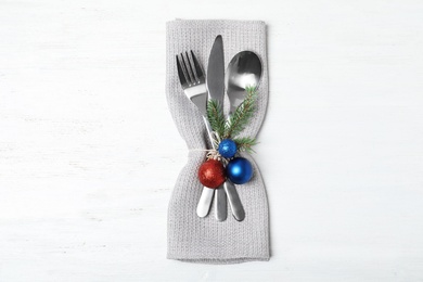 Cutlery, napkin and Christmas decor on wooden background, top view. Festive table setting