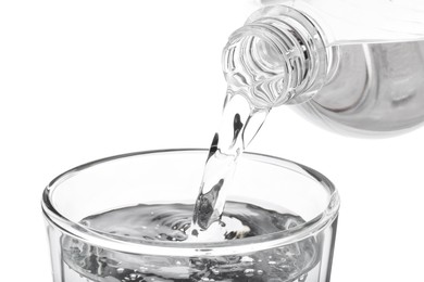 Photo of Pouring soda water from bottle into glass on white background, closeup
