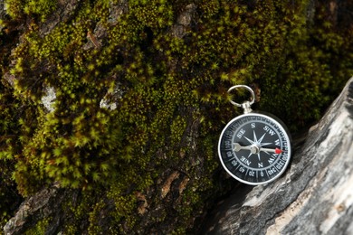 Compass on tree covered with moss, top view. Space for text