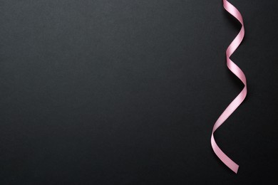 Photo of Beautiful pink ribbon on black background, top view. Space for text