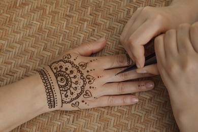 Master making henna tattoo on hand, top view. Traditional mehndi