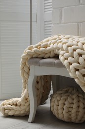 Indoor bench with soft chunky knit blanket and pouf in room. Interior design