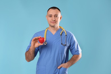 Photo of Doctor with stethoscope and red heart on light blue background. Cardiology concept