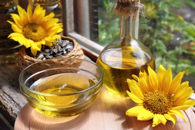 Organic sunflower oil and flowers on window sill indoors, closeup