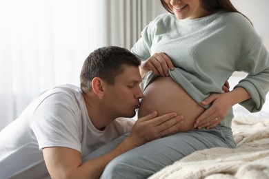 Young pregnant woman with her husband in bedroom, closeup