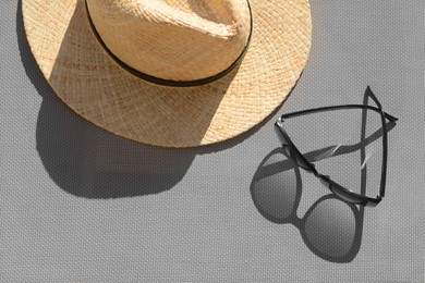 Stylish sunglasses and straw hat on grey surface, flat lay
