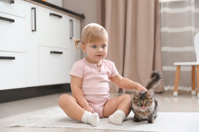 Cute little child with adorable pet on floor at home