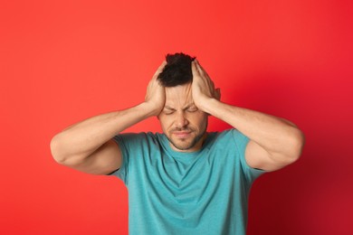 Man suffering from terrible migraine on red background