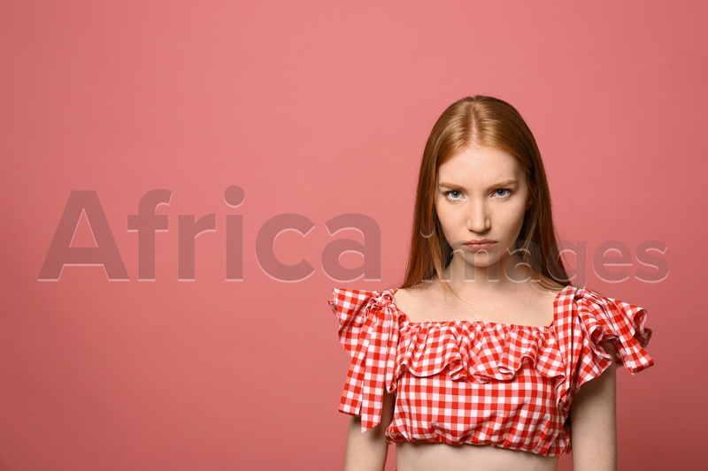 Portrait of angry young woman on pink background