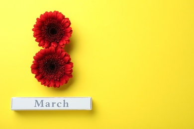 8 March greeting card design with red gerberas and space for text on yellow background, flat lay. International Women's day