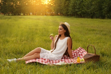 Young woman sitting on picnic blanket in park
