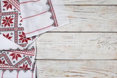 Beautiful rushnyk on white wooden table, top view with space for text. Ukrainian national embroidery