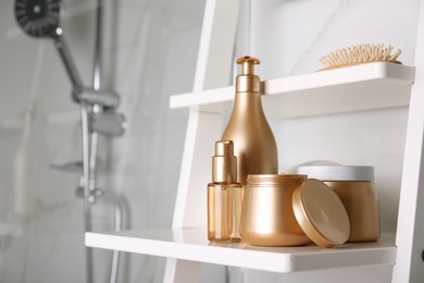 Different hair care products and brush on shelving unit in bathroom