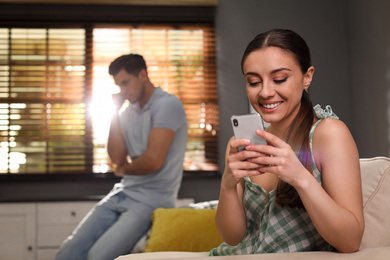 Woman preferring smartphone over spending time with her boyfriend at home. Jealousy in relationship