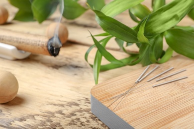 Wooden board with needles for acupuncture on table, closeup