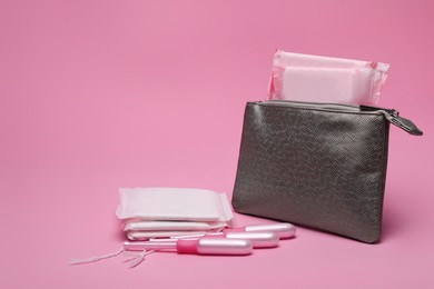 Silver bag, menstrual pads and tampons on pink background