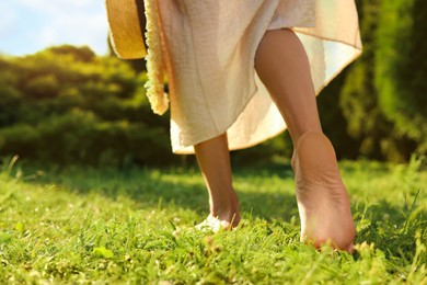 Woman walking barefoot on green grass outdoors, closeup. Space for text