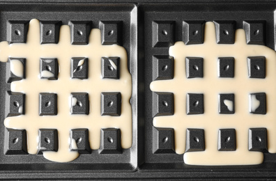Photo of Belgian waffle maker with dough, top view