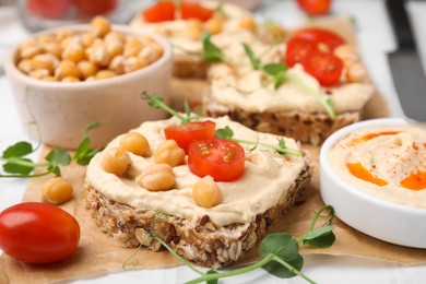 Delicious sandwiches with hummus and ingredients on wooden board, closeup