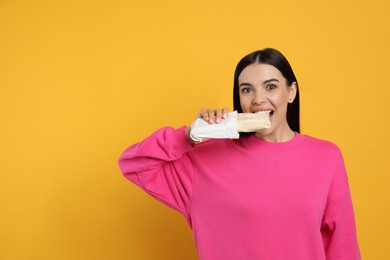 Young woman eating delicious shawarma on yellow background