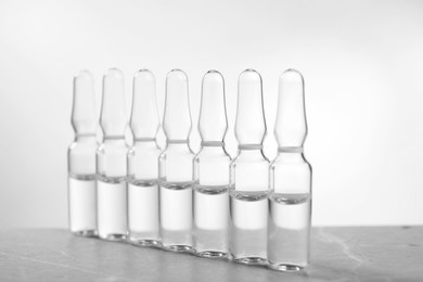 Pharmaceutical ampoules with medication on grey table against light background