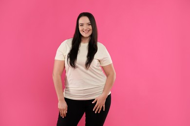 Beautiful overweight woman with charming smile on pink background