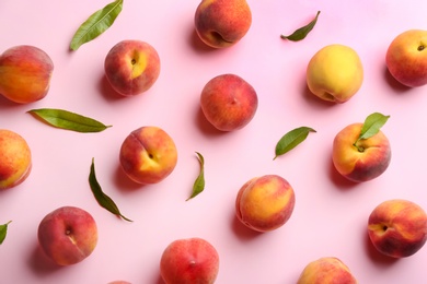 Fresh ripe peaches and green leaves on pink background, flat lay