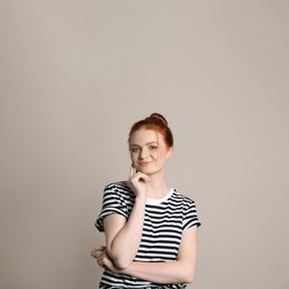 Candid portrait of happy red haired woman with charming smile on beige background