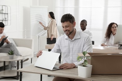 Photo of New coworker with laptop at workplace in office