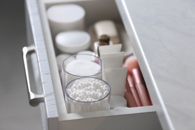 Open cabinet drawer with cotton buds and pads indoors, closeup