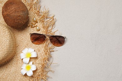 Flat lay composition with stylish sunglasses and straw hat on sand. Space for text